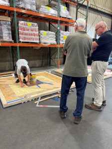 Judges watch Powell working on wood installation TISE Boston regional